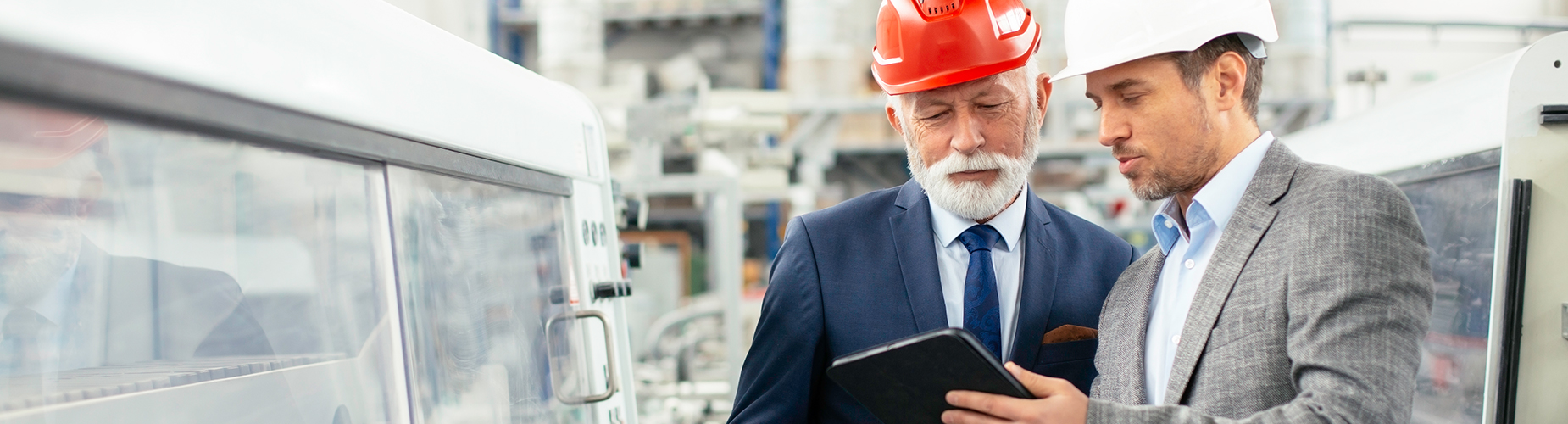 Zwei Männer diskutieren vor einem Tablet in einer Maschinenhalle